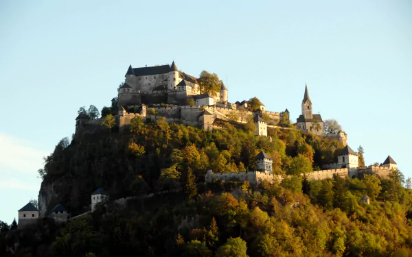 A stunning 4K Ultra HD wallpaper showcasing Hochosterwitz Castle perched atop a lush, forested hill under a clear sky.