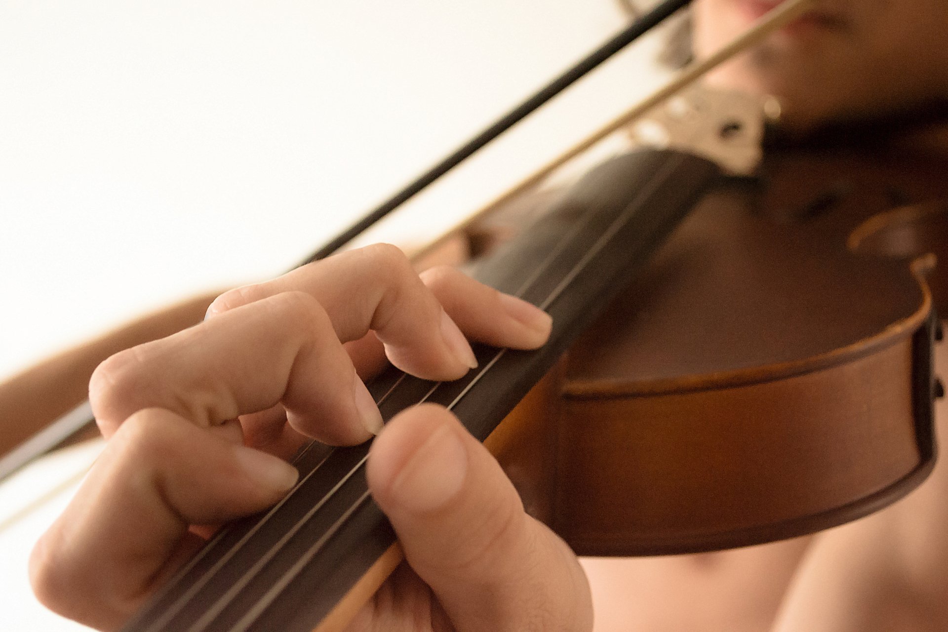 Close-up of hands playing a violin, captured in 4K Ultra HD for a PC desktop wallpaper and background showcasing music and string instrument detail.