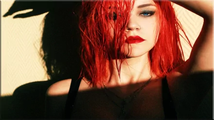 HD desktop wallpaper featuring a redhead woman model with striking red hair and bold makeup, partially illuminated by sunlight against a neutral background.