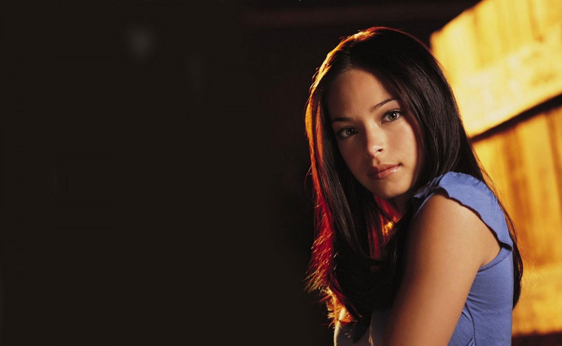 A stunning HD wallpaper featuring Kristin Kreuk, showcasing her captivating gaze and long, dark hair against a softly lit background.