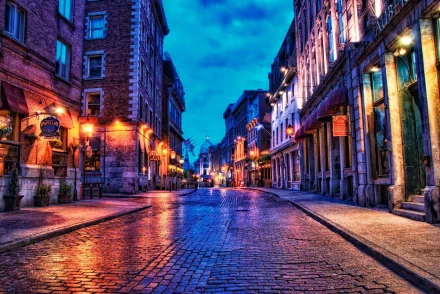 A vibrant HDR image of a cobbled street in Montreal, illuminated by warm light under a dramatic sky, showcasing the city's urban charm and architectural beauty.