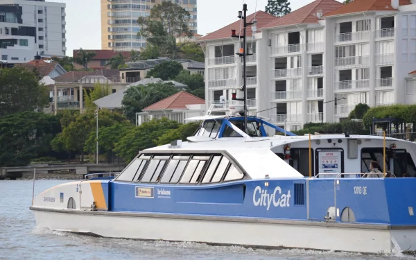 Passenger ferry CityCat glides on Brisbane's water with city buildings and greenery in the background, captured in a clear HD desktop wallpaper image.