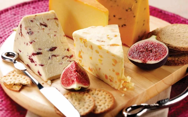 HD PC desktop wallpaper featuring a close-up of assorted cheeses, crackers, and figs arranged on a wooden serving board.