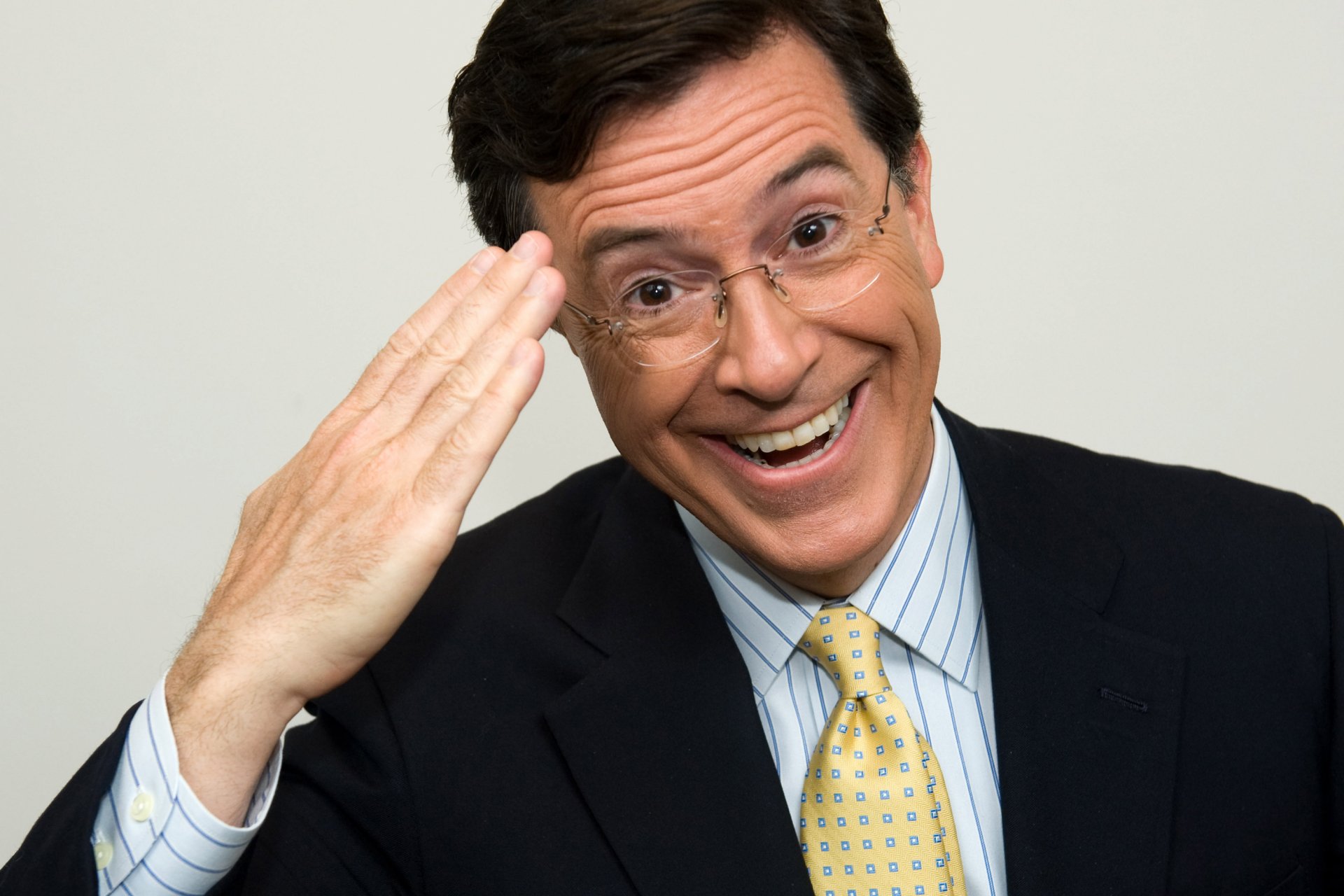HD desktop wallpaper of Stephen Colbert from The Colbert Report, smiling with a hand salute.