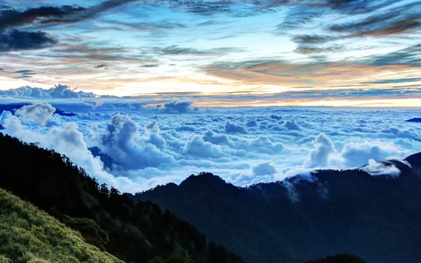HD desktop wallpaper showing a breathtaking sea of clouds above mountain peaks under a vibrant sky, capturing the serene beauty of nature.