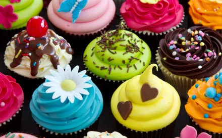 HD desktop wallpaper featuring an array of vibrant, decorated cupcakes with various toppings like sprinkles, chocolate, and edible flowers.