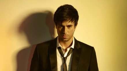 A striking HD desktop wallpaper featuring Enrique Iglesias, showcasing a close-up of him in a sleek suit, highlighting his intense expression against a warm background.