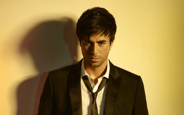 A striking HD desktop wallpaper featuring Enrique Iglesias, showcasing a close-up of him in a sleek suit, highlighting his intense expression against a warm background.