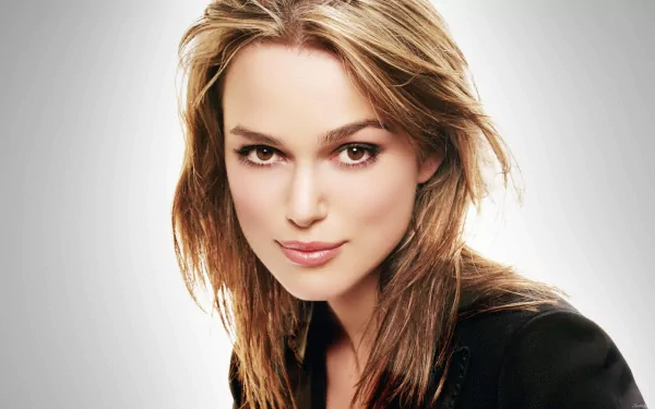 HD wallpaper featuring celebrity Keira Knightley, showcasing her confident expression and stylish look against a soft, gradient background.