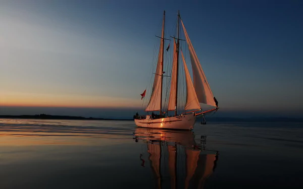 A serene sailboat glides across calm waters at sunset, reflecting vibrant colors against the peaceful background, creating an engaging HD wallpaper for your PC.