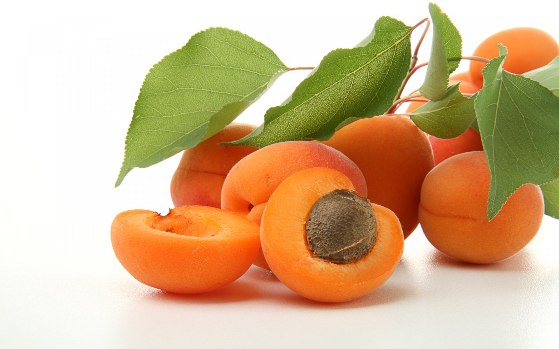 A vibrant display of fresh peaches and peach halves surrounded by green leaves, making a colorful and appetizing HD PC desktop wallpaper and background.