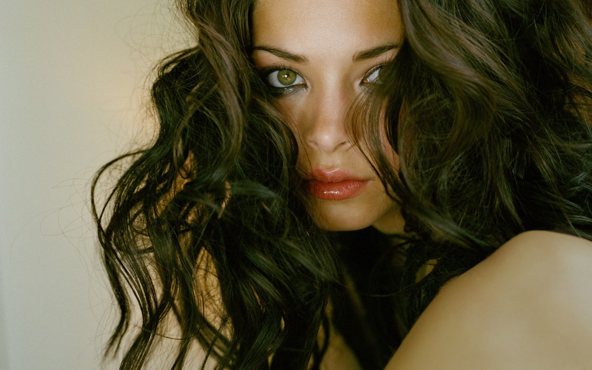 HD PC desktop wallpaper featuring a close-up portrait of celebrity Kirstin Kreuk with dark, wavy hair and expressive eyes.
