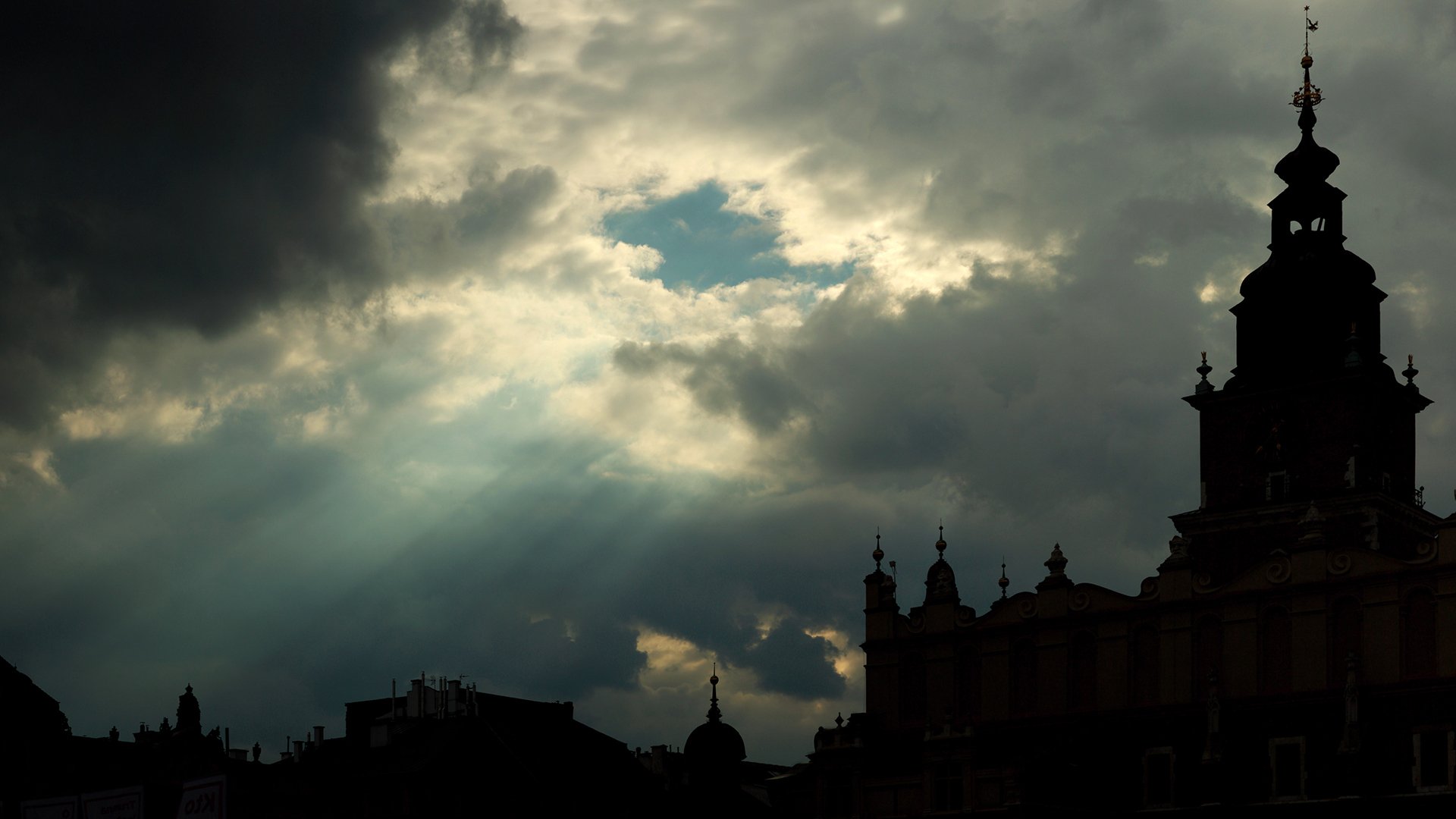 Photography: dramatic sunbeam piercing storm clouds over a silhouetted city skyline — HD PC desktop wallpaper and background