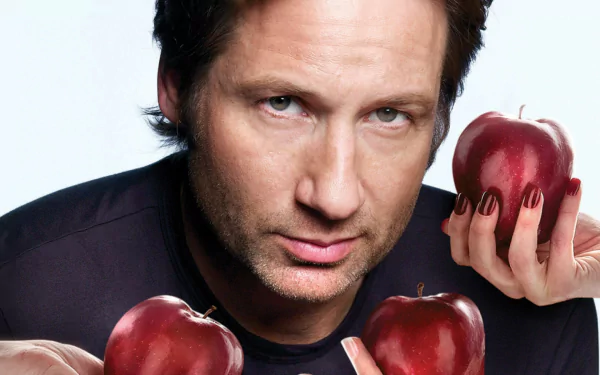 Close-up HD desktop wallpaper of a man staring at the camera, hands holding glossy red apples in the foreground.