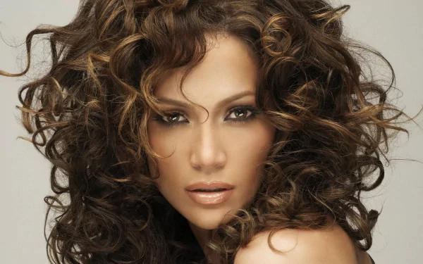 A stunning HD wallpaper featuring Jennifer Lopez, showcasing her signature curly hair and captivating expression against a soft background.
