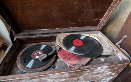 A vintage photograph featuring an old phonograph with vinyl records and a weathered book, creating a nostalgic atmosphere. This image serves as a captivating HD desktop wallpaper.