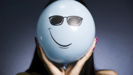 HD PC desktop wallpaper featuring a funny smiley face with sunglasses drawn on a light blue balloon held in front of a dark background.