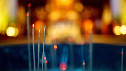 Photography of an incense stick glowing with ember and warm bokeh lights — HD PC desktop wallpaper and background.