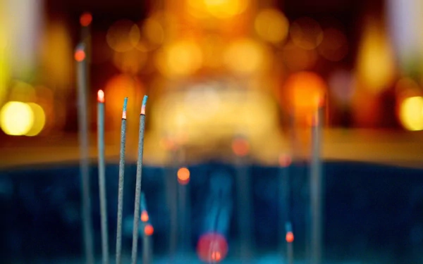 Photography of an incense stick glowing with ember and warm bokeh lights — HD PC desktop wallpaper and background.