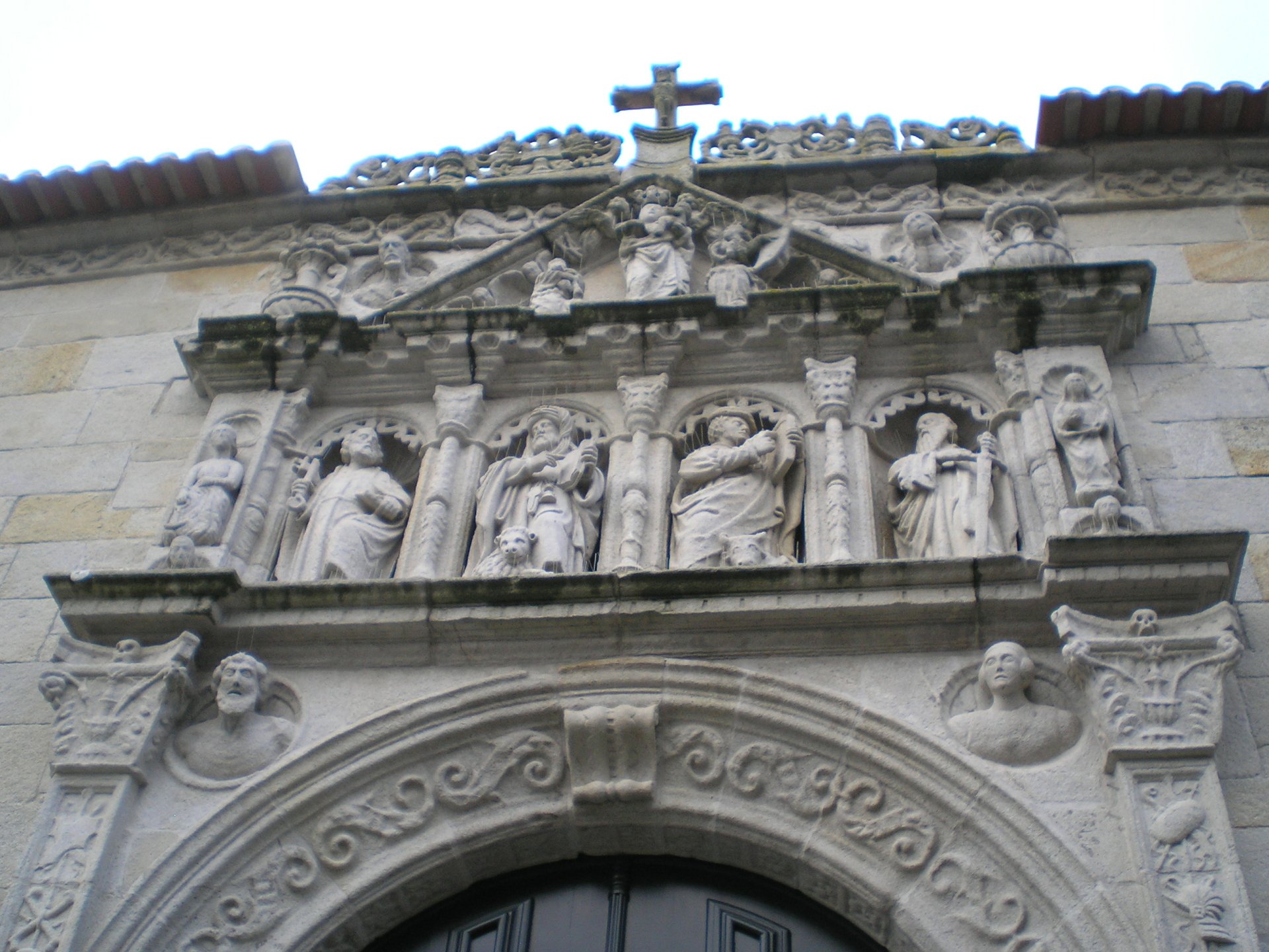 HD wallpaper depicting ornate religious Christian stone carvings and sculptures on a church facade, with intricate details and a cross at the top.