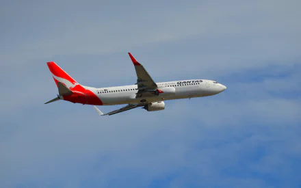 A Qantas Boeing 737 soaring through a clear sky, showcasing its distinctive red and white livery, set against a serene backdrop—an engaging HD desktop wallpaper for aviation enthusiasts.