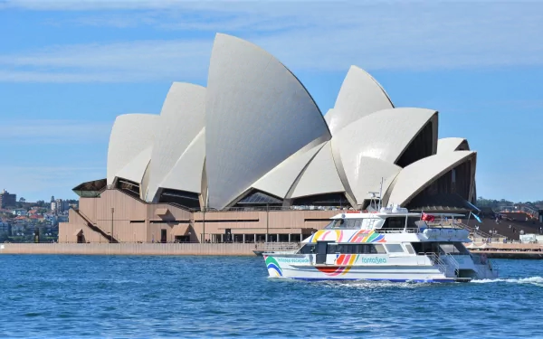 Ferry boat sailing in Sydney Harbour with the iconic Sydney Opera House and Circular Quay buildings in the background on a clear day in Australia.