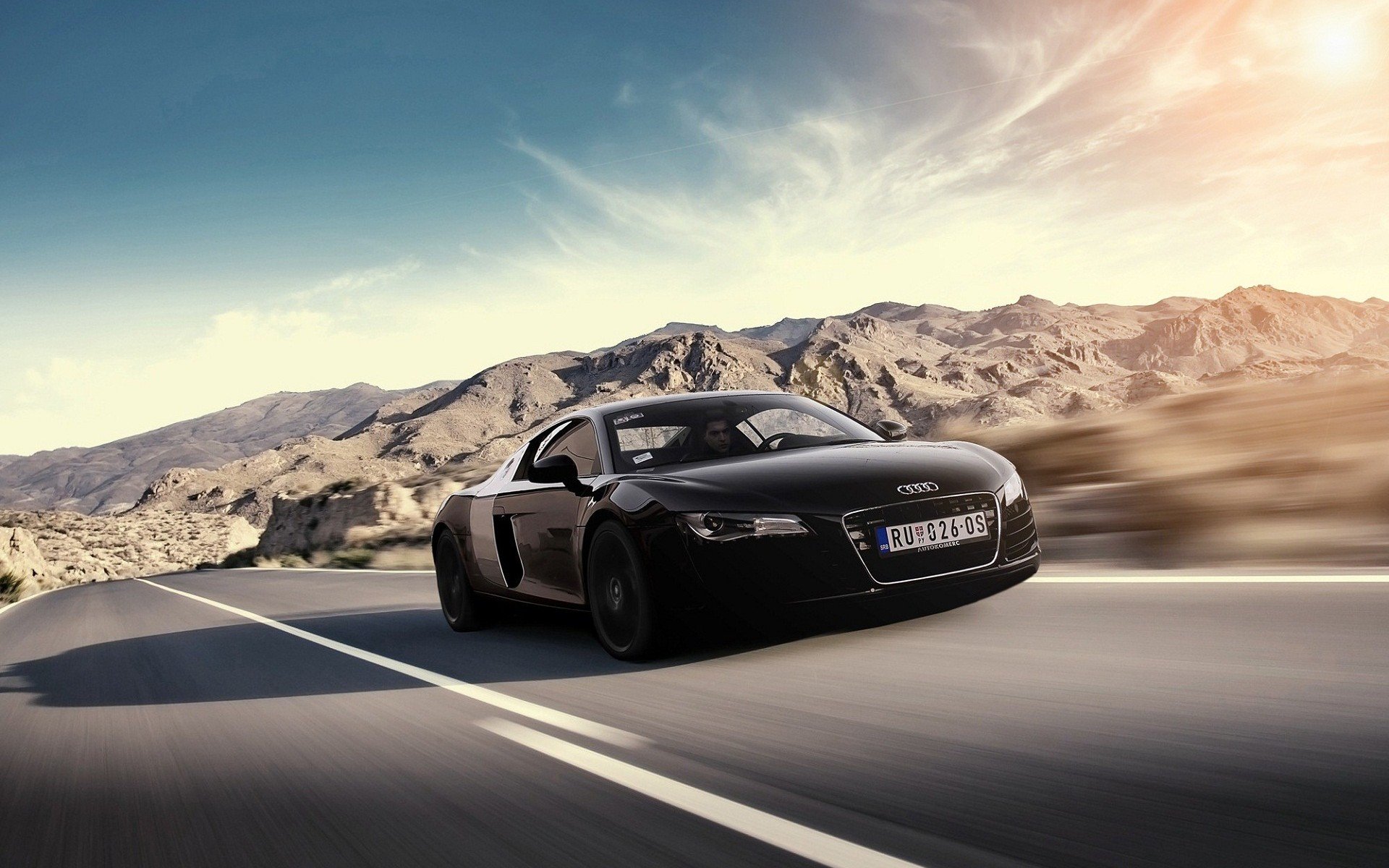 Sleek black Audi sports car racing along a desert highway at sunset — HD PC desktop wallpaper background of a high-speed vehicle.