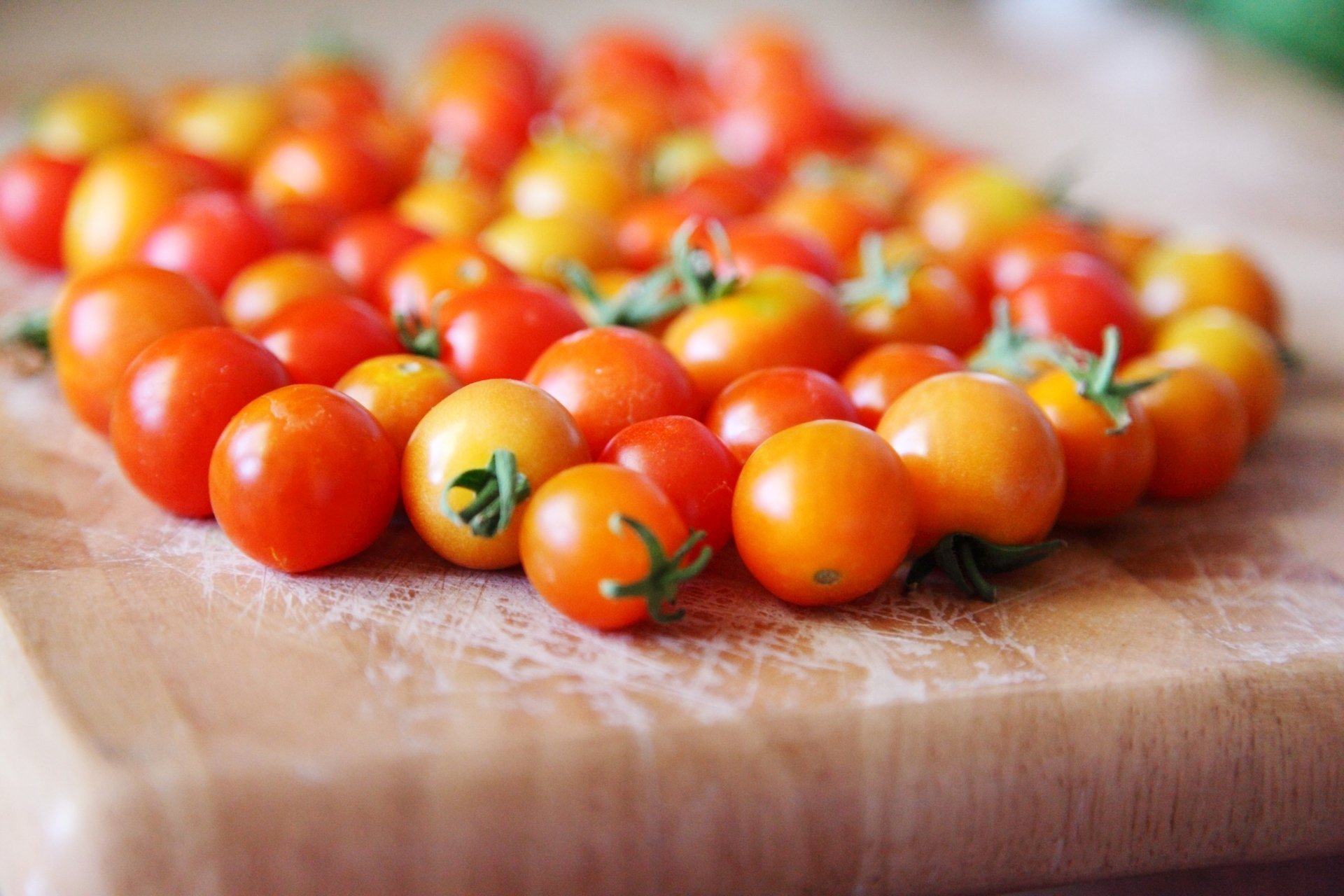 Close-up of ripe cherry tomatoes arranged on a wooden surface, captured in high definition for a vibrant PC desktop wallpaper and background.