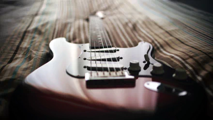 HD PC desktop wallpaper featuring a close-up of an electric guitar lying on a wooden surface, highlighting its strings and body for a music-themed background.