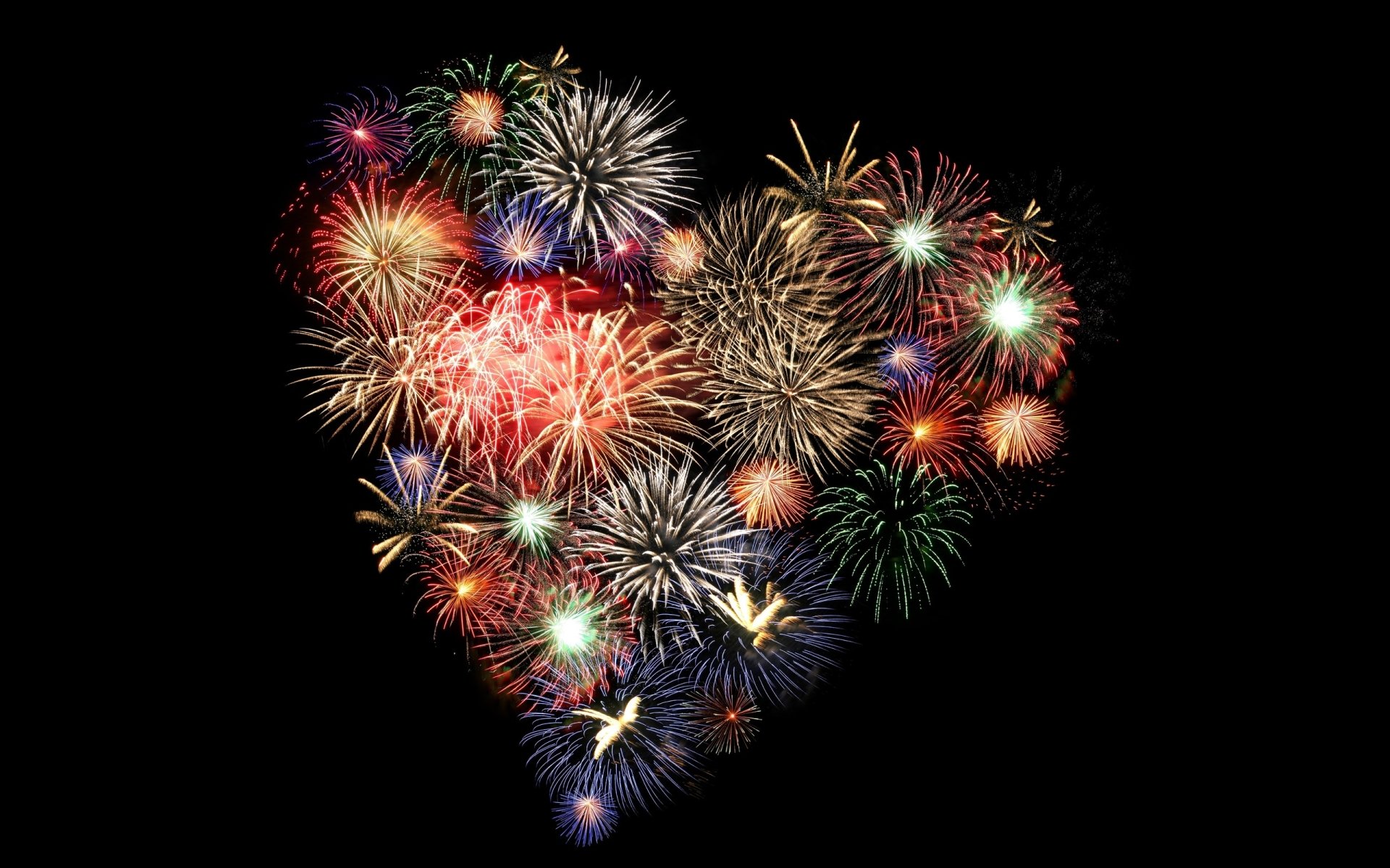 A vibrant display of colorful fireworks arranged in a heart shape against a dark background. This striking image serves as an HD desktop wallpaper, adding a festive touch to any screen.