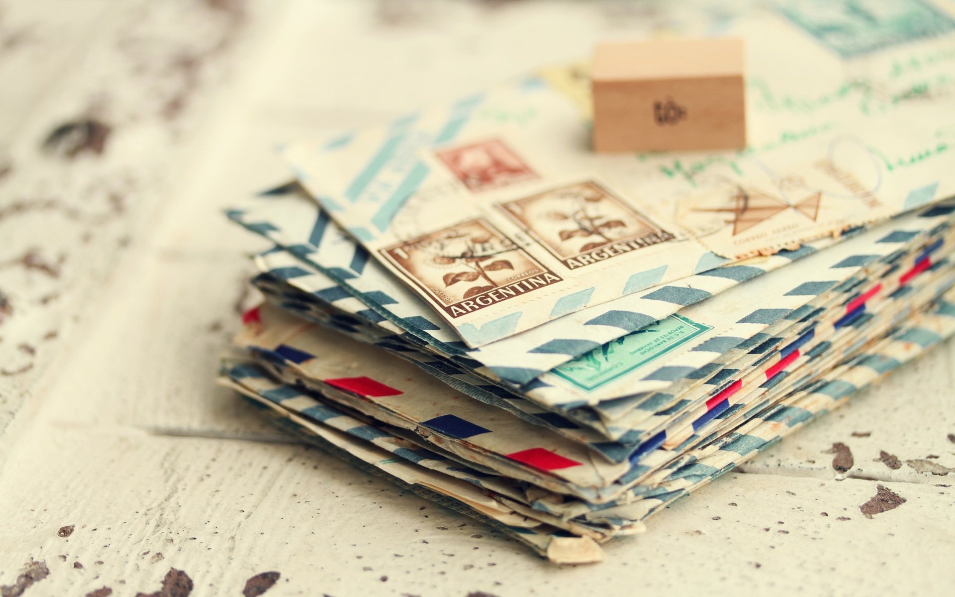 Vintage-style photography of a stack of airmail envelopes with postage stamps, captured in high definition as a PC desktop wallpaper and background.