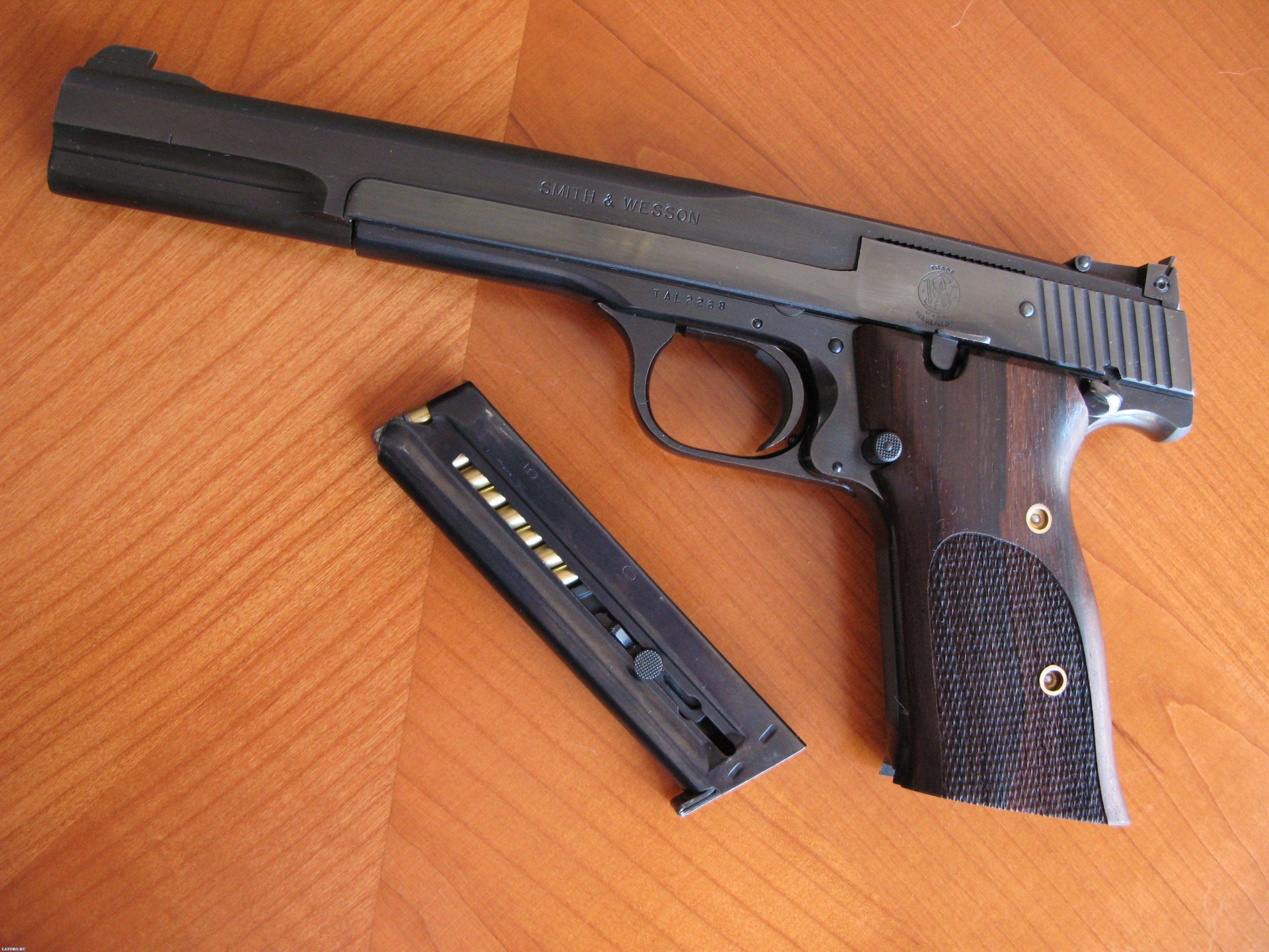 Smith & Wesson man-made pistol with detached magazine on a wooden surface, presented as a 2K Quad HD PC desktop wallpaper and background.