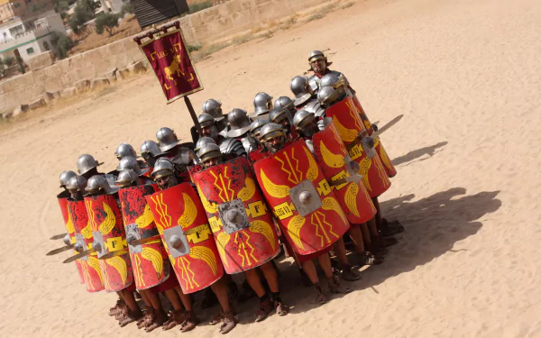 Armored man and warriors form a Roman-style testudo beneath a banner — 4K Ultra HD PC desktop wallpaper and background.