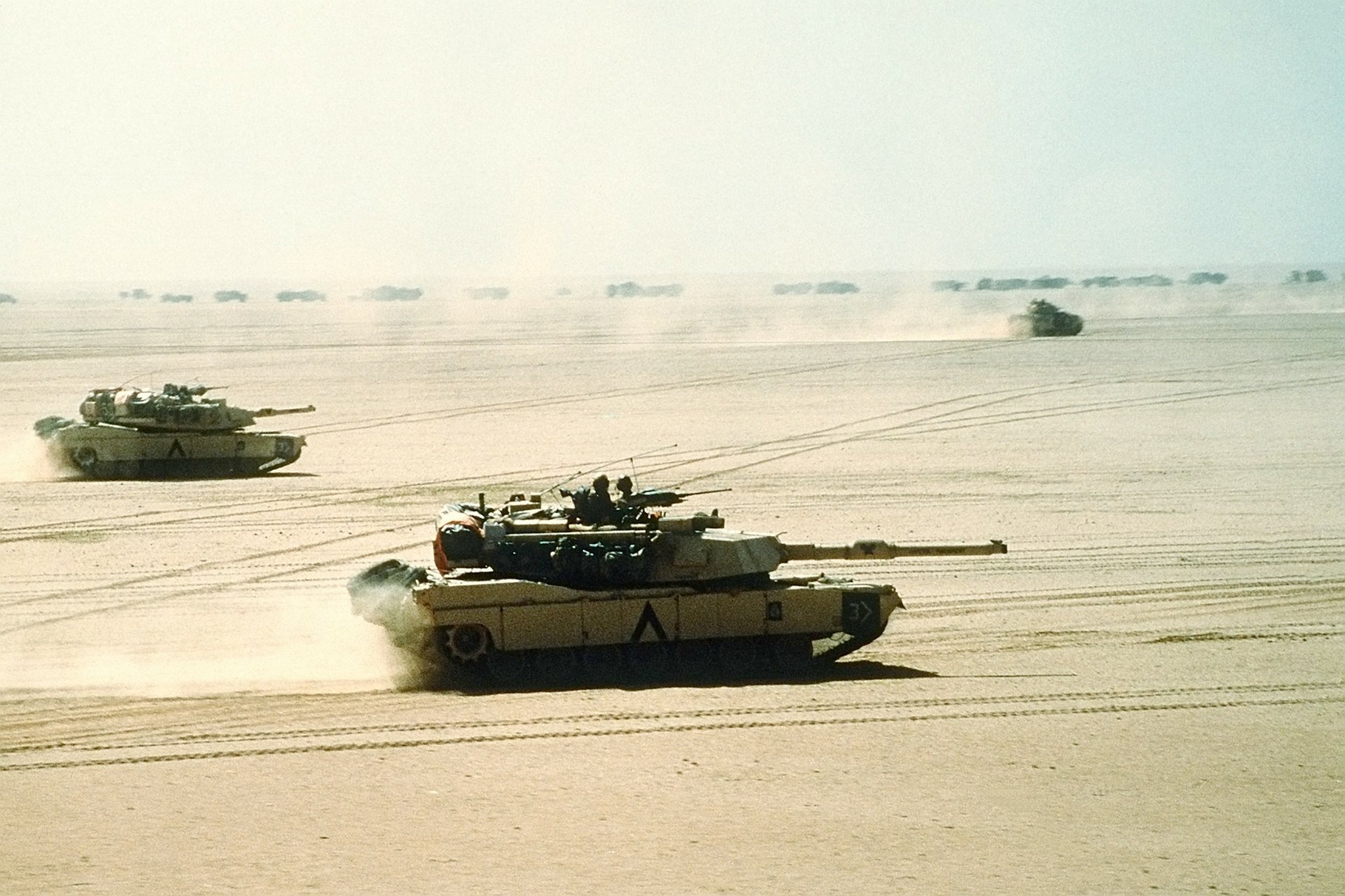 HD PC desktop wallpaper showing military tanks advancing across a sandy desert during the Gulf War.