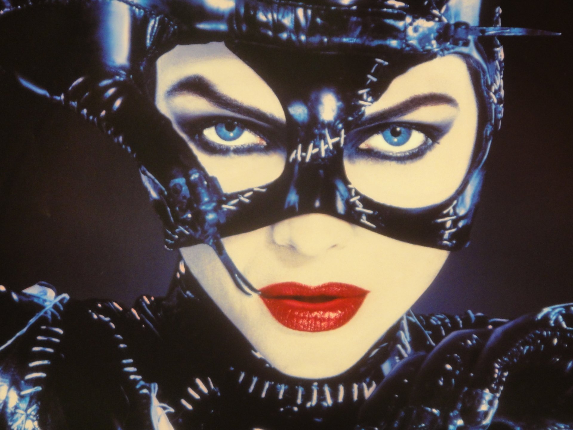 Close-up of Catwoman from the movie Batman Returns — stitched black mask, piercing blue eyes and red lips; 2K Quad HD PC desktop wallpaper/background.