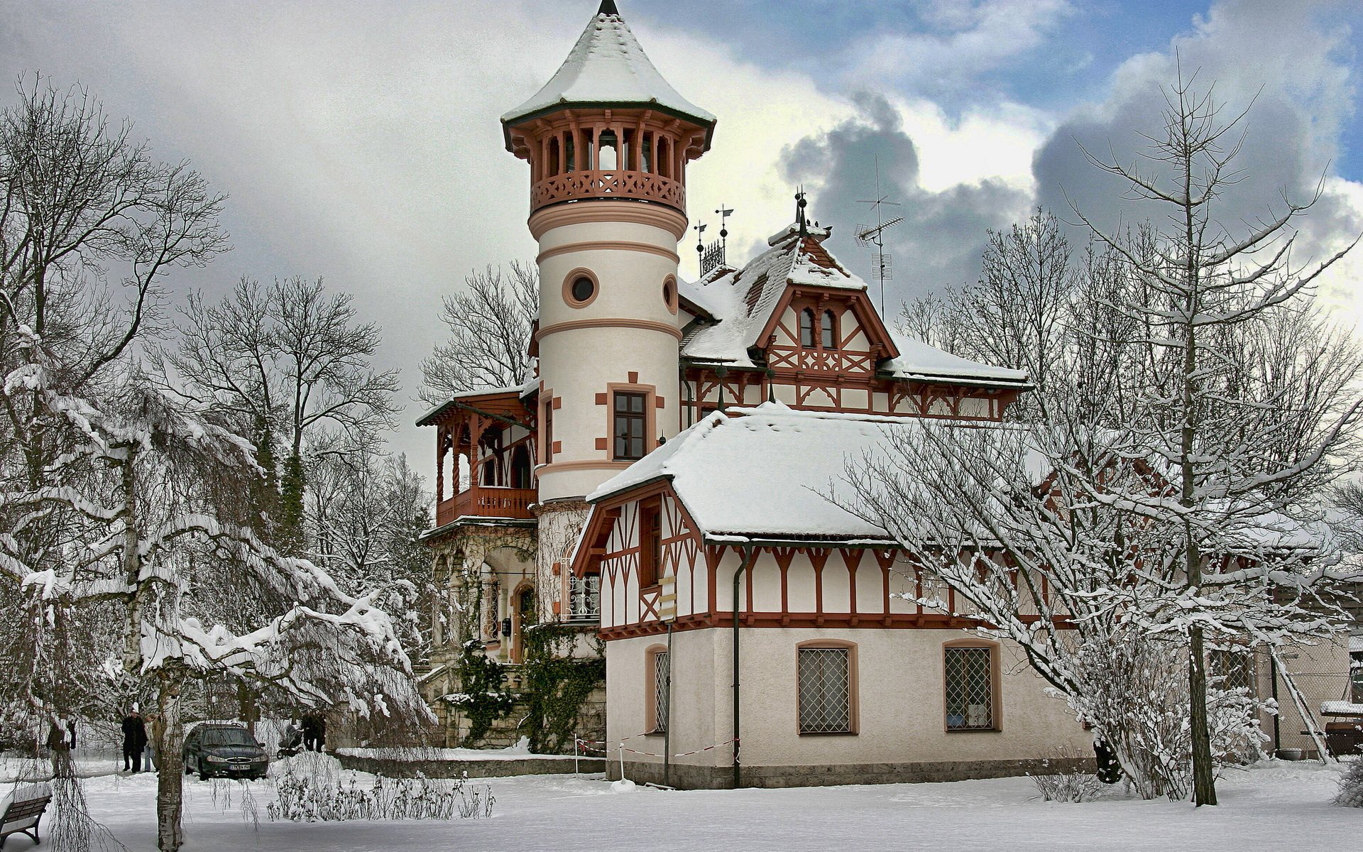HD desktop wallpaper of a man-made villa covered in snow, surrounded by bare trees under a cloudy sky.