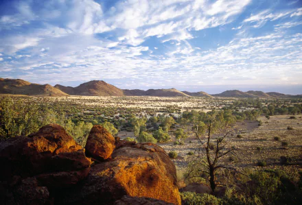 2K Quad HD PC desktop wallpaper: panoramic nature view of the Flinders Ranges — rocky foreground, scattered trees and distant ridges beneath a cloud-streaked sky.