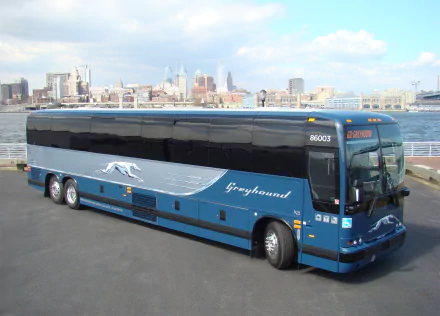HD desktop wallpaper of a blue Greyhound bus parked by the waterfront with a city skyline in the background.