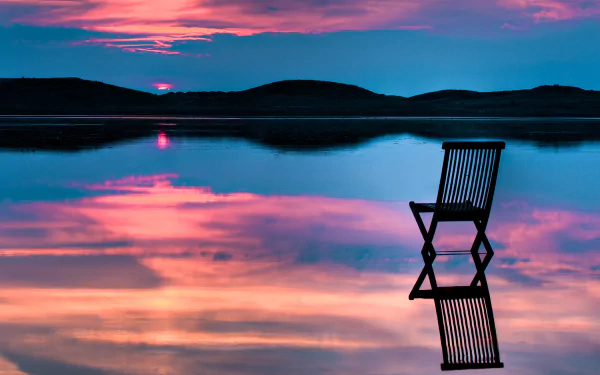 HD desktop wallpaper featuring a serene landscape with a single chair facing a beautifully reflective water body under a twilight sky.