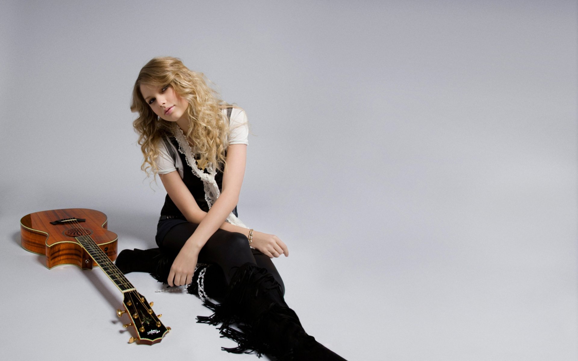 HD desktop wallpaper featuring Taylor Swift seated with a guitar on a minimalist gray background, creating an elegant and music-themed backdrop.