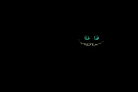 HD desktop wallpaper featuring the glowing eyes and wide smile of the Cheshire Cat from the 2010 movie Alice in Wonderland against a black background.