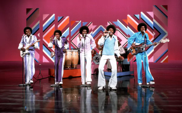 HD PC desktop wallpaper featuring The Jackson 5 performing on a vibrant stage with colorful geometric patterns, capturing the energy of classic music icons.