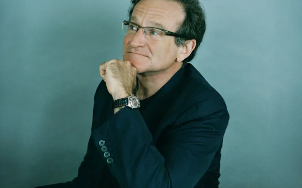 HD desktop wallpaper featuring a pensive man sitting with his chin resting on his hand, against a grey backdrop.