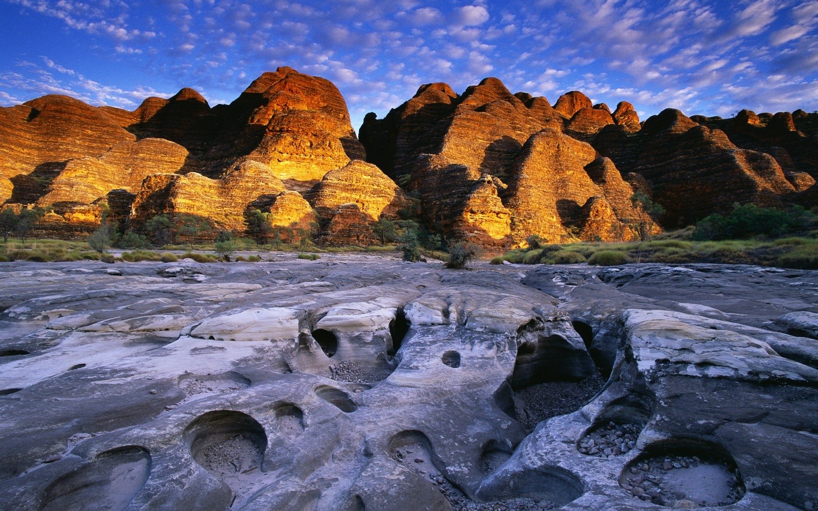 HD desktop wallpaper showcasing the rugged, sunlit rock formations of the Kimberley region under a vibrant blue sky dotted with clouds.