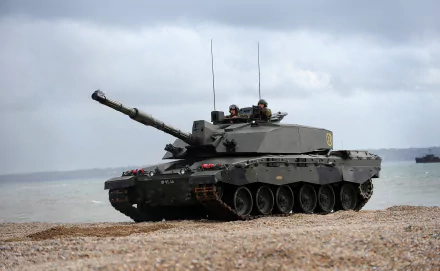 HD desktop wallpaper depicting a Challenger 2 military tank positioned on a rocky beach under a cloudy sky.