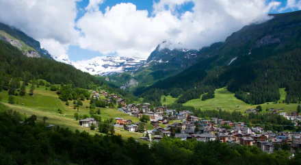 A stunning view of a Swiss village nestled in the mountains, showcasing lush greenery, snow-capped peaks, and a picturesque lake, capturing the natural beauty of Montreux and its surroundings.