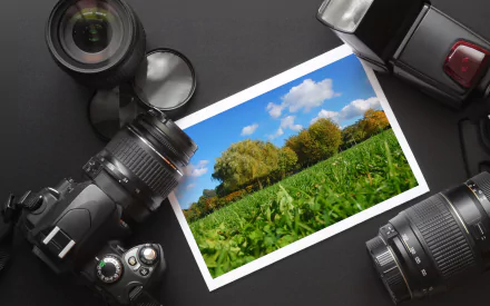 A collection of cameras surrounds a vibrant landscape photograph, set against a sleek black background, creating a striking HD desktop wallpaper.