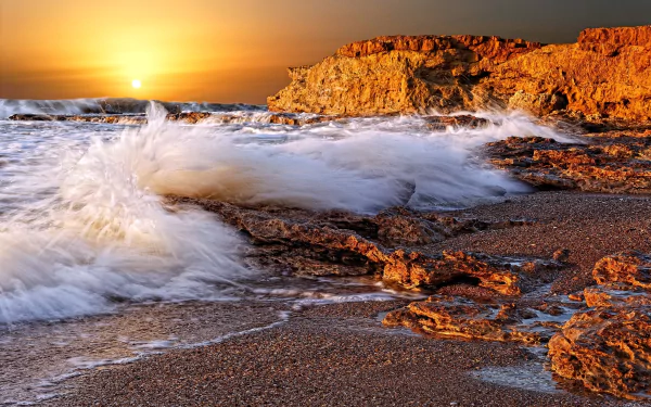 A stunning HD wallpaper featuring a serene coastline at sunset, with waves crashing against rocky shorelines, capturing the beauty of nature in vibrant colors.