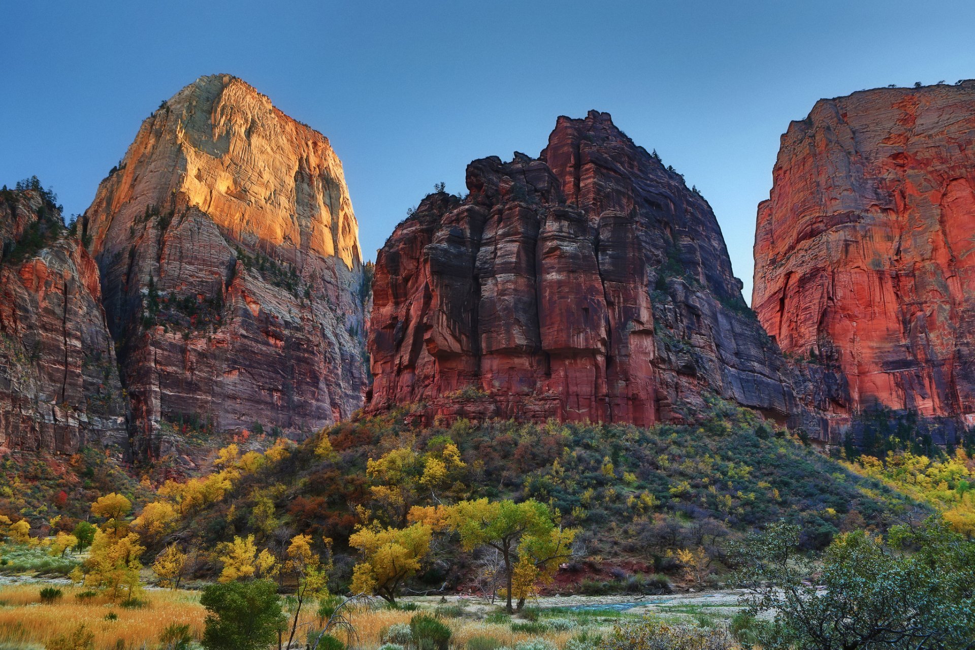 HD PC desktop wallpaper of a stunning canyon landscape with towering red rock formations and vibrant autumn foliage under a clear blue sky.