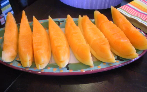 2K Quad HD PC desktop wallpaper of honeydew melon slices arranged on a colorful platter; food, melon.